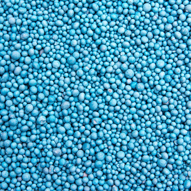 Grânulos azuis de vários tamanhos, vistos de perto, mostrando a área de Fertilizantes TMSA